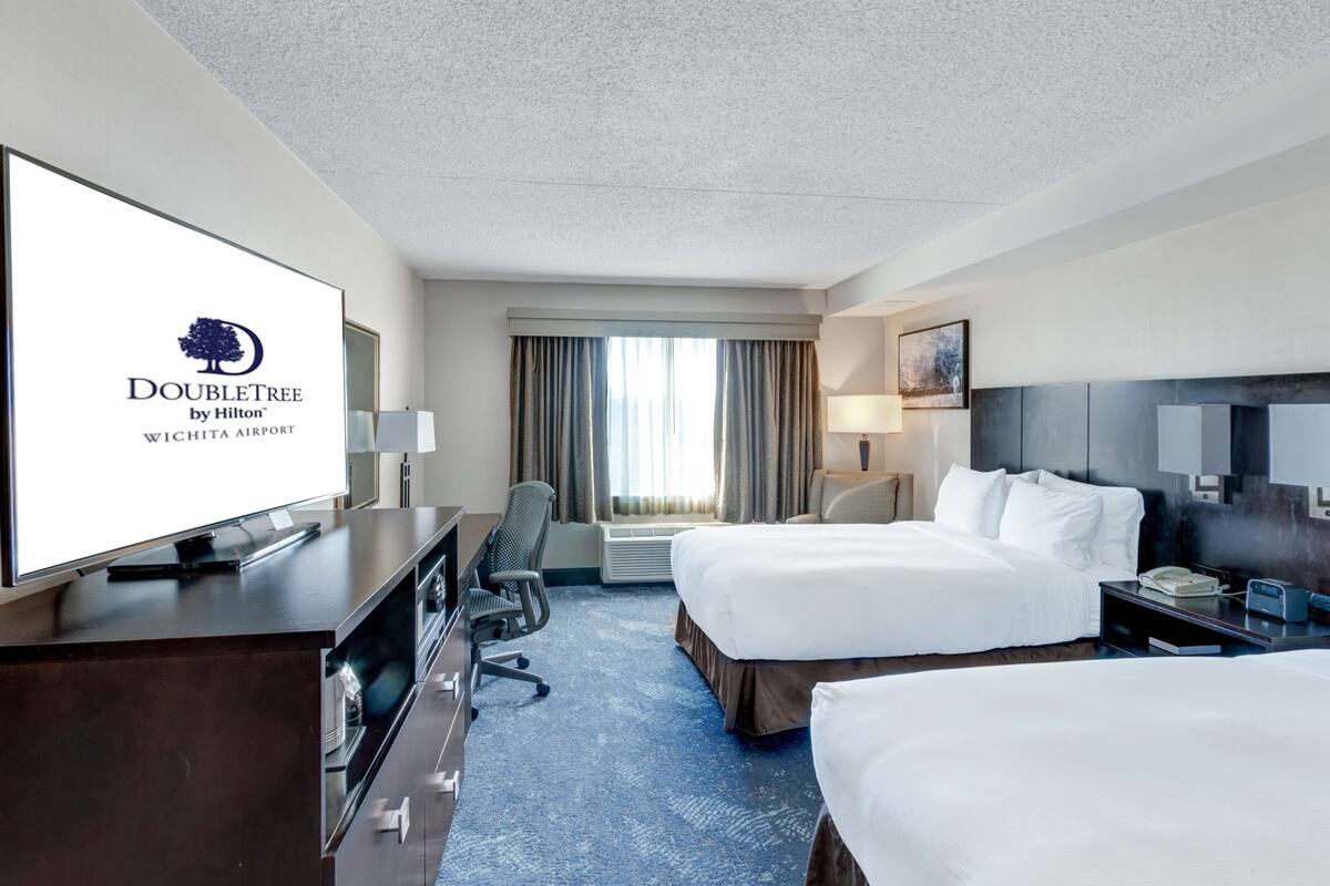 A DoubleTree by Hilton hotel room with two beds, a desk, a TV, and a large window with curtains.