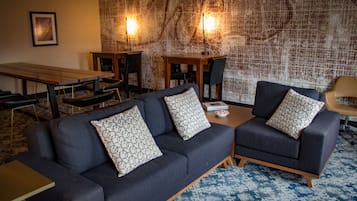 A modern living room with a dark blue sofa set, a wooden coffee table, and a patterned wall.