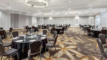 A large conference room with round tables and chairs, a patterned carpet, and a chandelier.