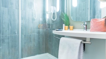 Een moderne badkamer met een douchecabine van glas, een witte wastafel, een spiegel en een handdoekrek.