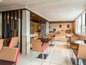 A modern cafe with a counter displaying pastries and a menu, surrounded by chairs and tables. - ibis Cognac Centre (Cognac)