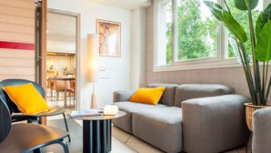Una sala de estar moderna con un sofá, una silla, una mesa de centro y un amplio ventanal con vistas al verdor.