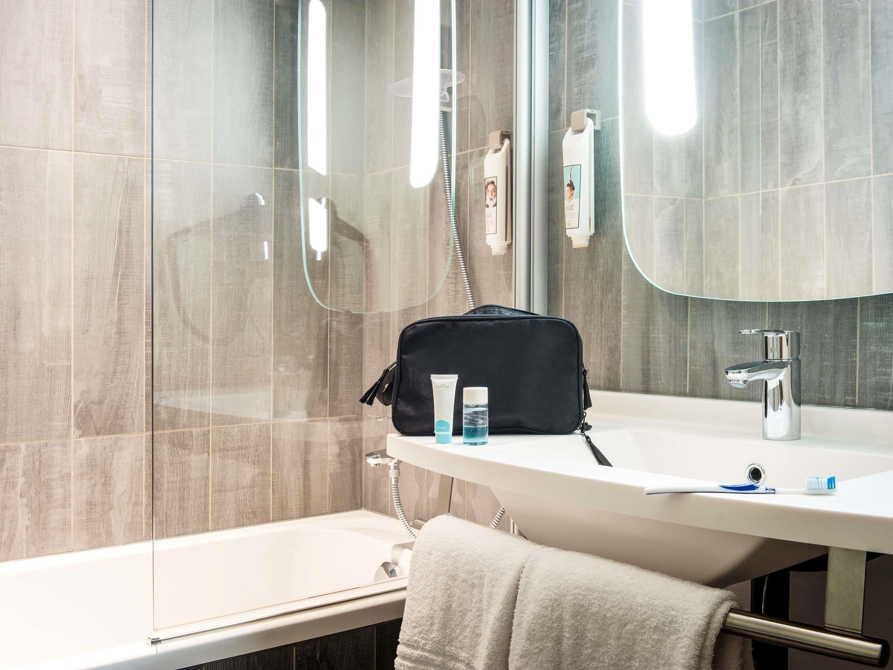 Une salle de bain moderne avec une douche à parois de verre, un lavabo blanc avec un miroir et un porte-serviettes.