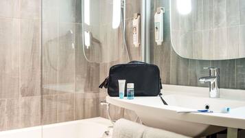 Une salle de bain moderne avec une douche à parois de verre, un lavabo blanc avec un miroir et un porte-serviettes.