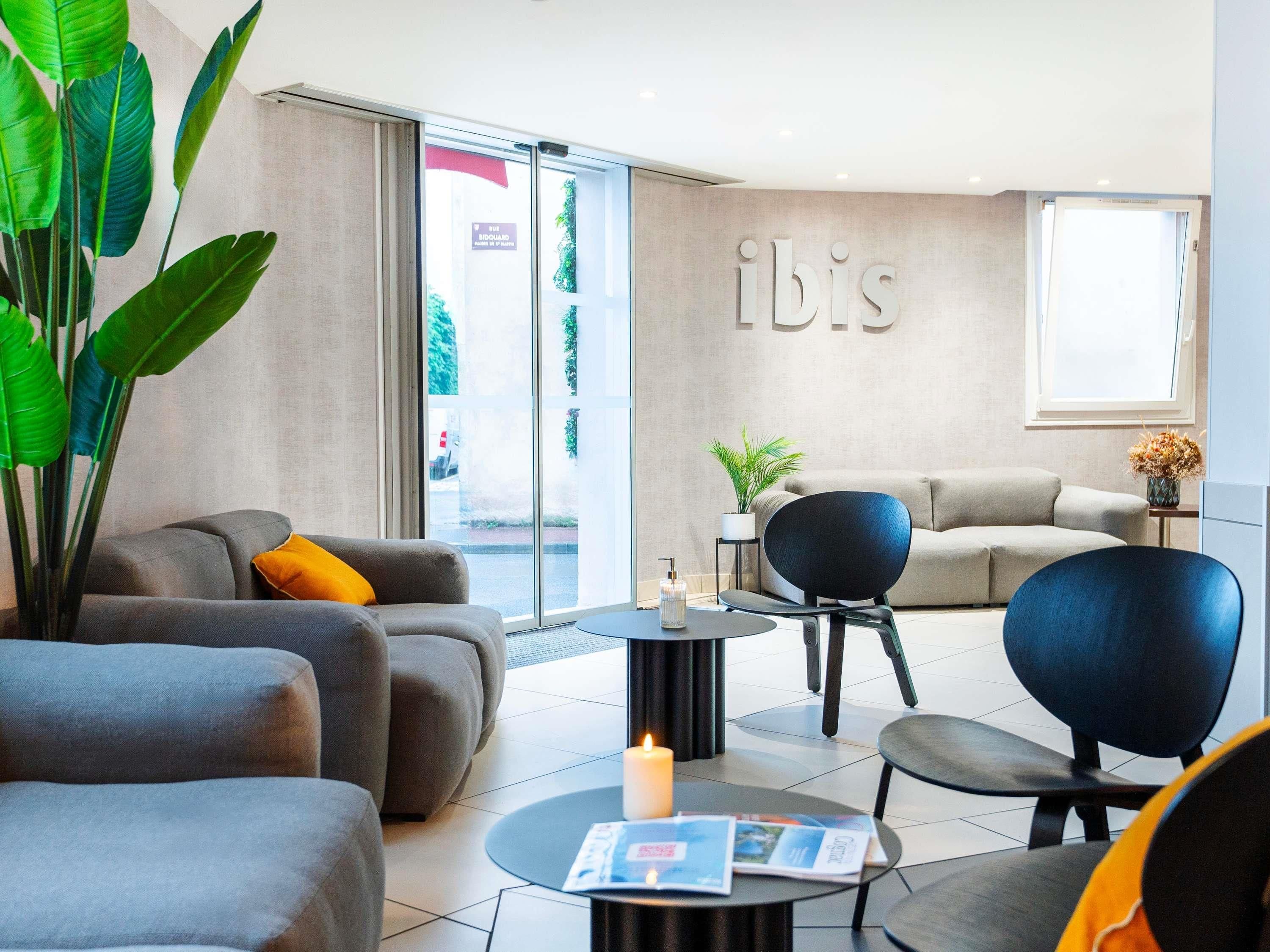 Un hall d’hôtel moderne avec des canapés, une table basse et une grande plante.