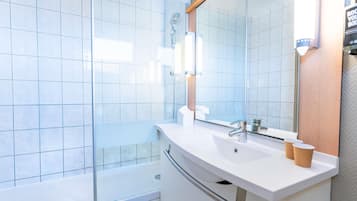 Ein modernes Badezimmer mit einer Duschkabine aus Glas, einem weißen Waschbecken und einem großen Spiegel.