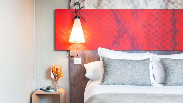 Een moderne slaapkamer met een bed, nachtkastje en een abstract schilderij boven het bed.