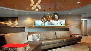 A modern lobby with a curved ceiling, a leather sofa with red cushions, and a unique chandelier. - SpringHill Suites Cincinnati North/Forest Park (Cincinnati)