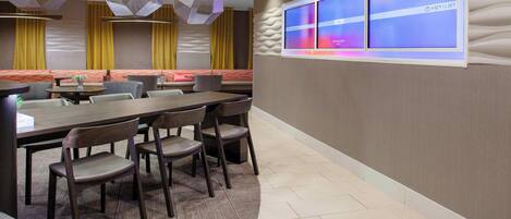 A modern conference room with a long table, multiple chairs, and a large digital display on the wall.