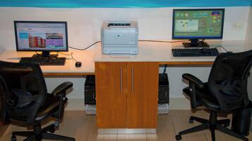 Un espacio de trabajo con dos monitores de computadora, una impresora y dos sillas de oficina.
