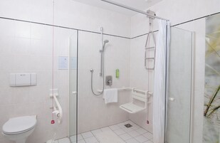 Uma casa de banho moderna com cabine de duche em vidro, sanita e secador de mãos.
