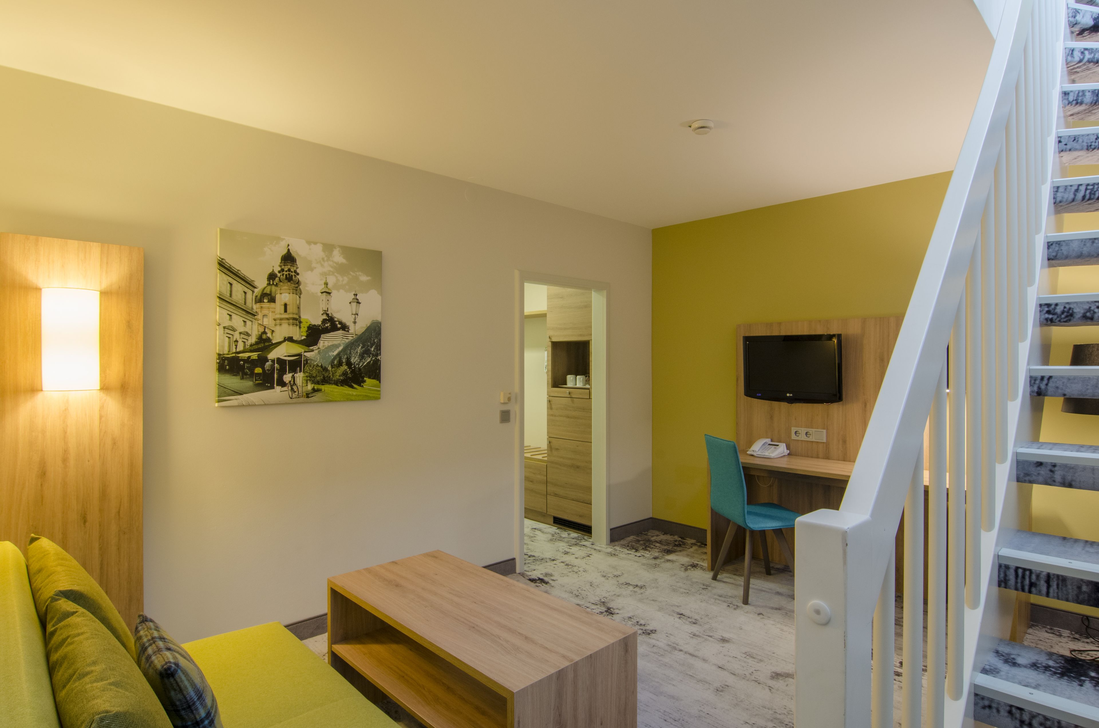 Una sala de estar moderna con un sofá, una mesa de centro, un cuadro y una escalera.