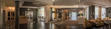 Um lobby de hotel moderno com balcão de recepção, áreas de estar e um centro de conferências.