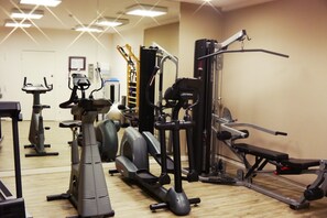 Une salle de sport équipée de divers appareils d’exercice, notamment des tapis de course, un appareil elliptique et une machine de musculation.