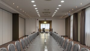 A conference room with a long table, chairs, and a clock on the wall. - Holiday Inn Munich-Unterhaching by IHG (Unterhaching)