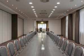 Une salle de conférence avec une longue table, des chaises et une horloge au mur.