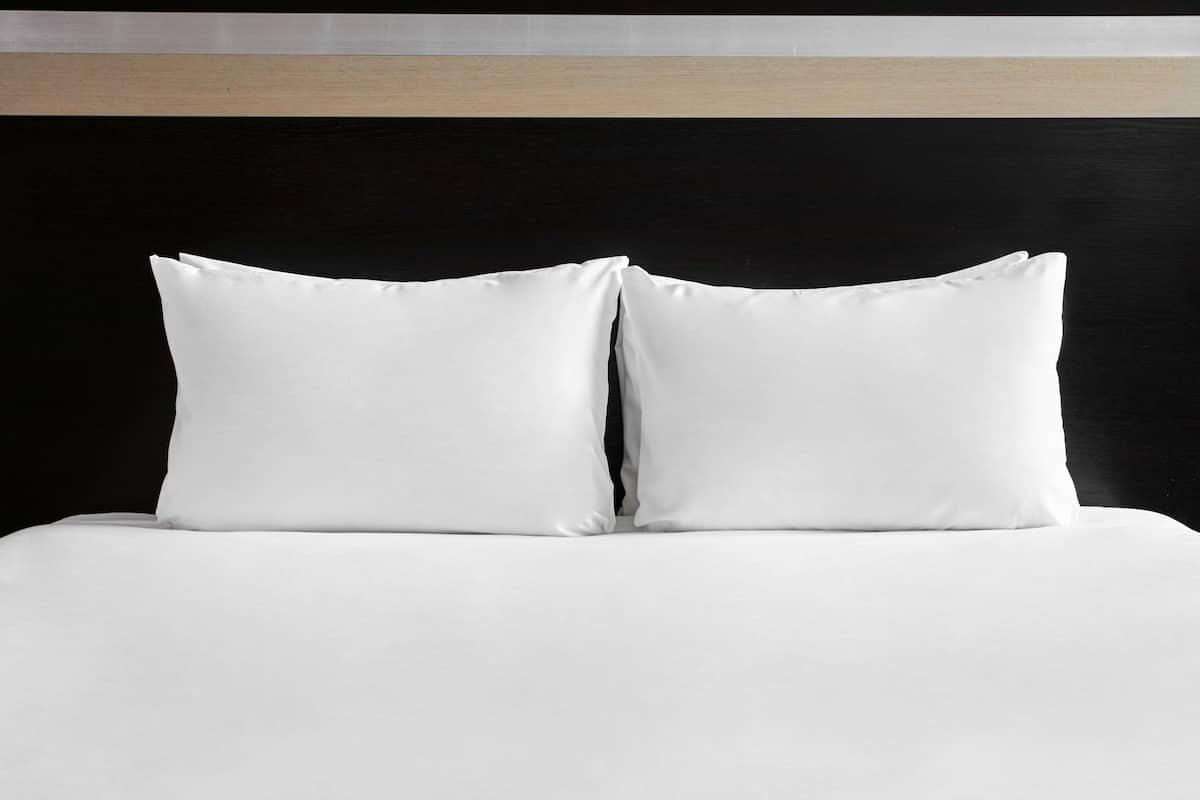 Un letto con biancheria bianca e due cuscini.