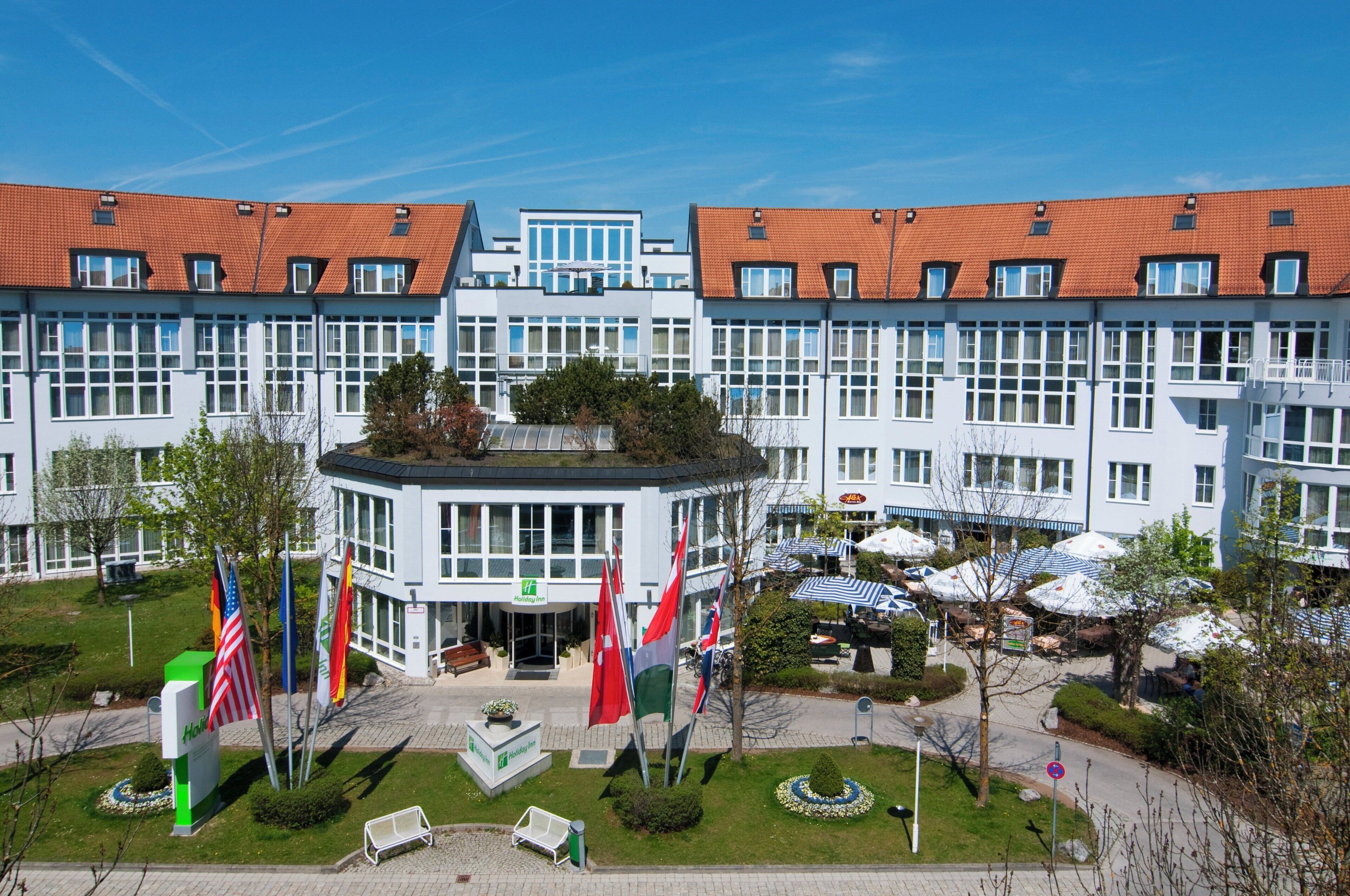 A hotel with a central courtyard, multiple flags, and outdoor seating.
