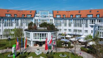 A hotel with a central courtyard, multiple flags, and outdoor seating.