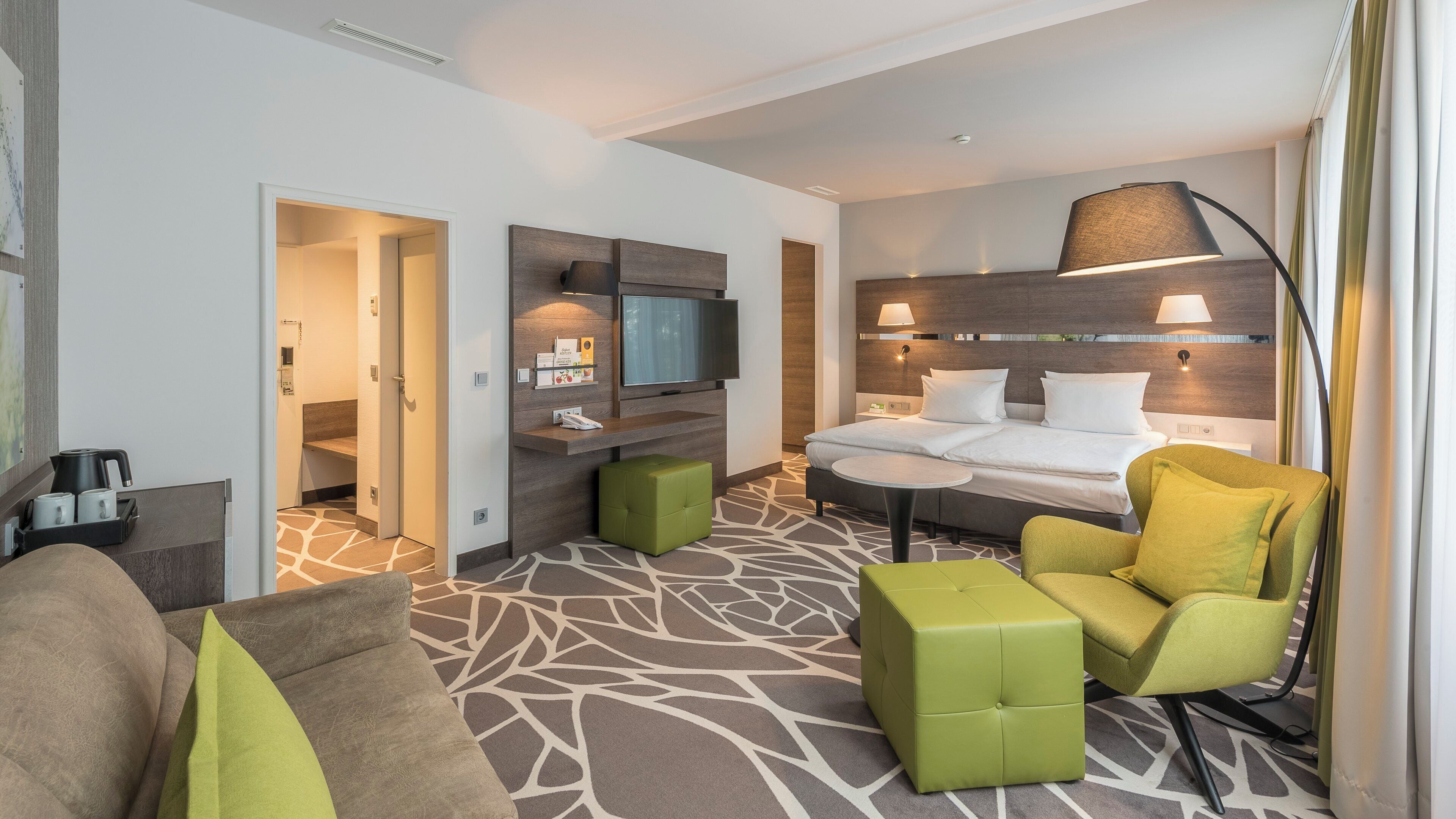 A hotel room with a bed, a desk, a television, a sofa, and a chair.