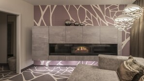 Un salon moderne avec une cheminée, un canapé gris et un mur orné de motifs.