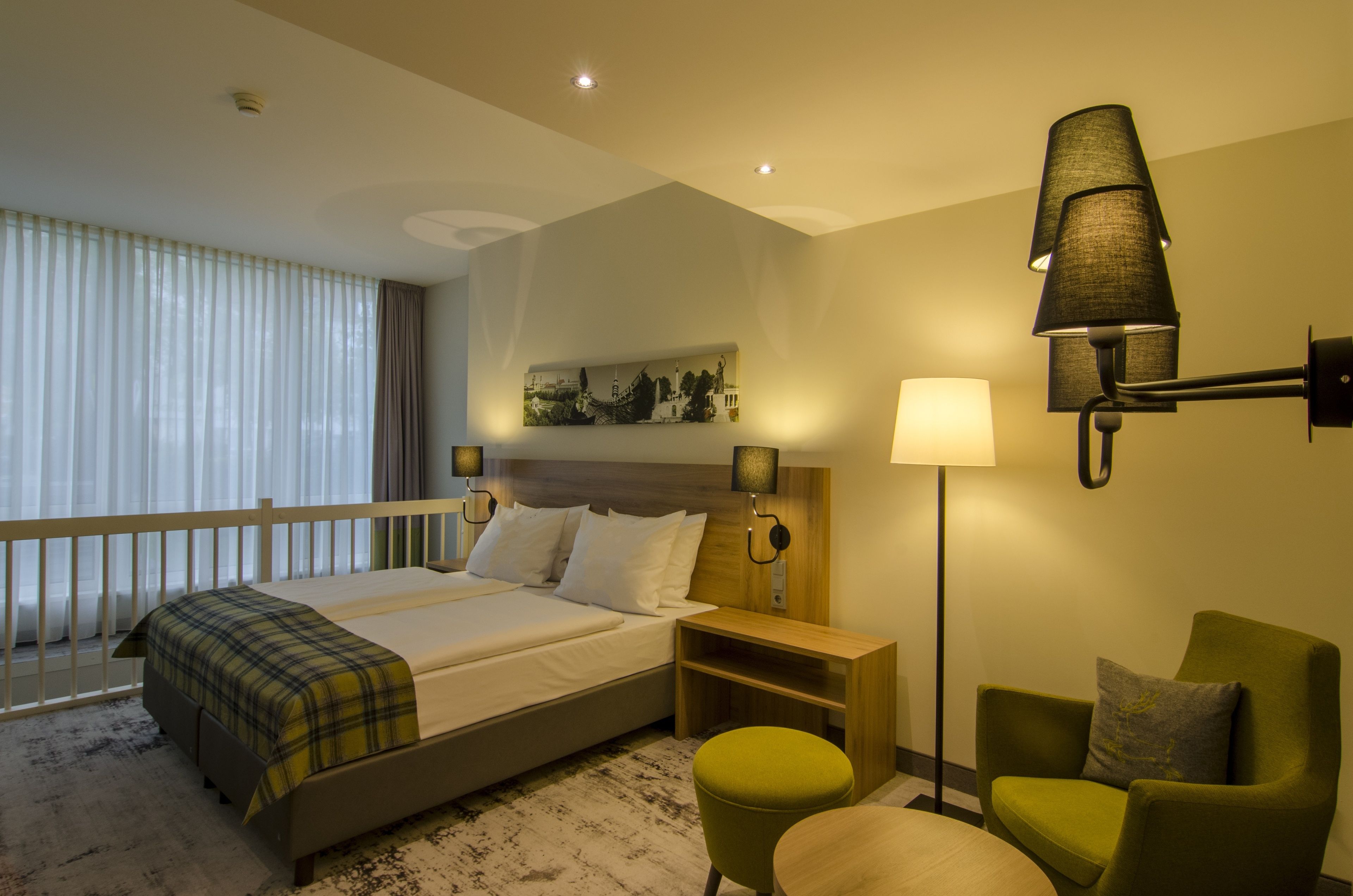 Une chambre d’hôtel avec un lit, une table de chevet, une lampe, une chaise et une vue sur l’extérieur par une fenêtre.