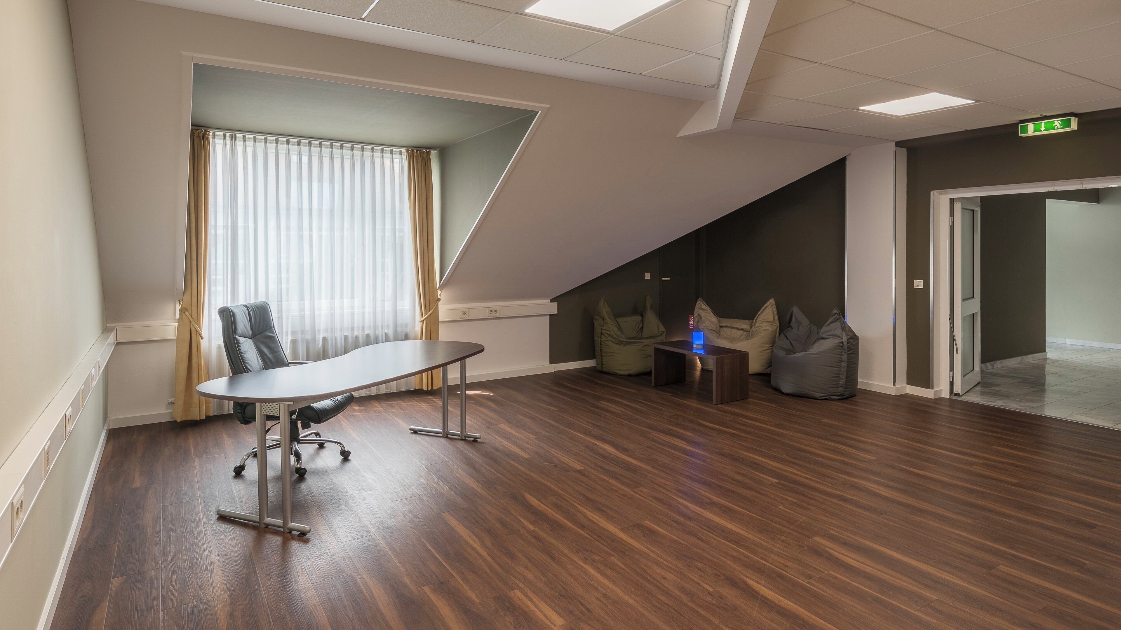 Une salle de conférence équipée d’une table, de chaises et de fauteuils en forme de poire (ou poufs).