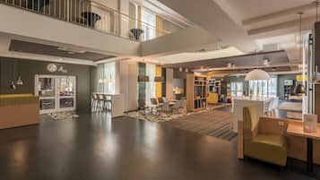Un vestíbulo amplio con una recepción, zona de estar y una escalera que conduce a un nivel superior.