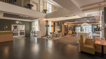 Um hall amplo com balcão de recepção, área de estar e escadaria para um andar superior.
