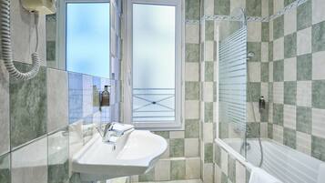 Une salle de bain avec une douche à parois de verre, un lavabo blanc et un téléphone.