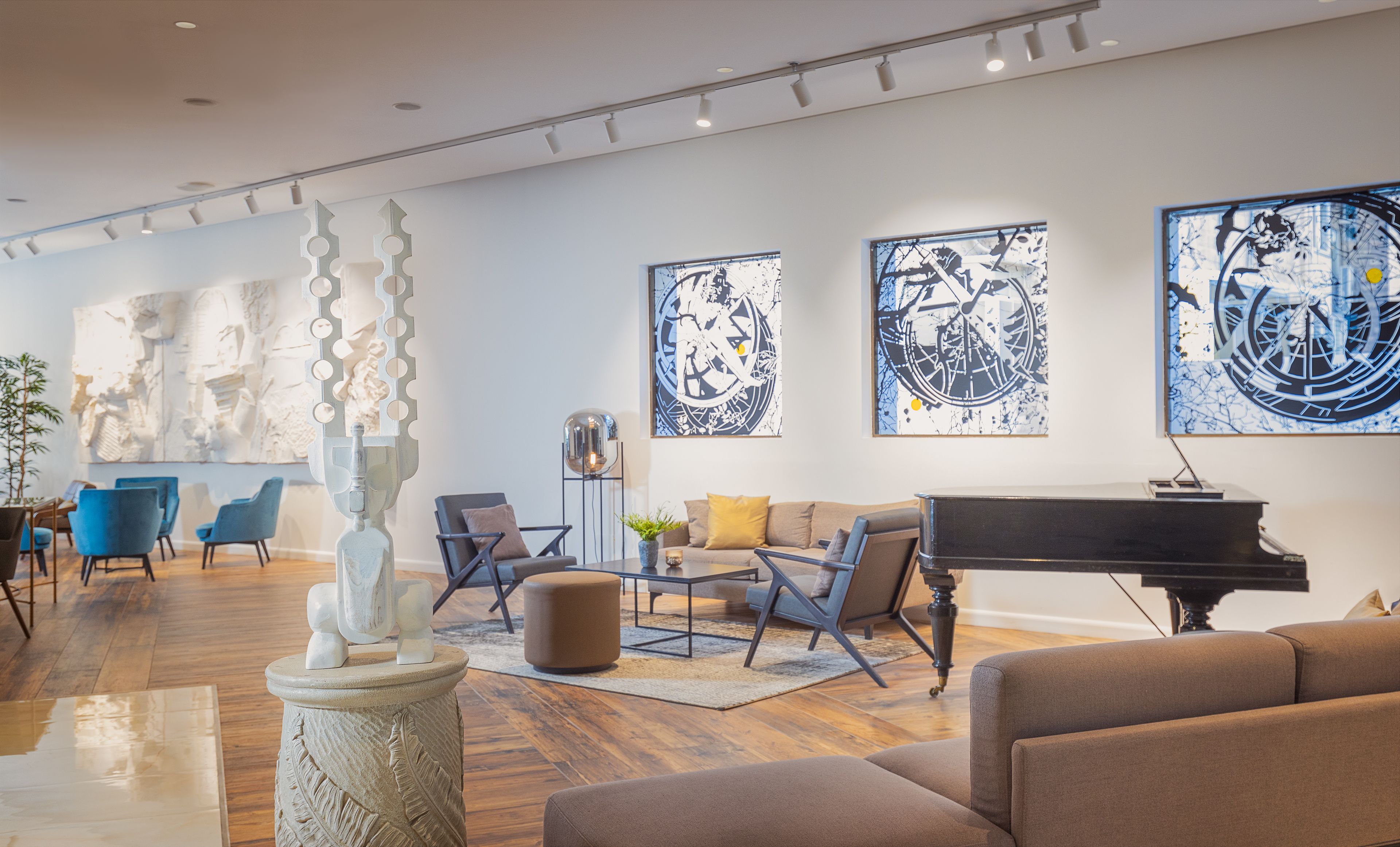 A modern living room with a grand piano, comfortable seating, and abstract art on the walls.