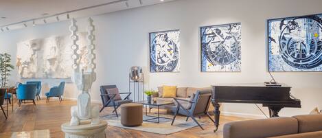 A modern living room with a grand piano, comfortable seating, and abstract art on the walls.