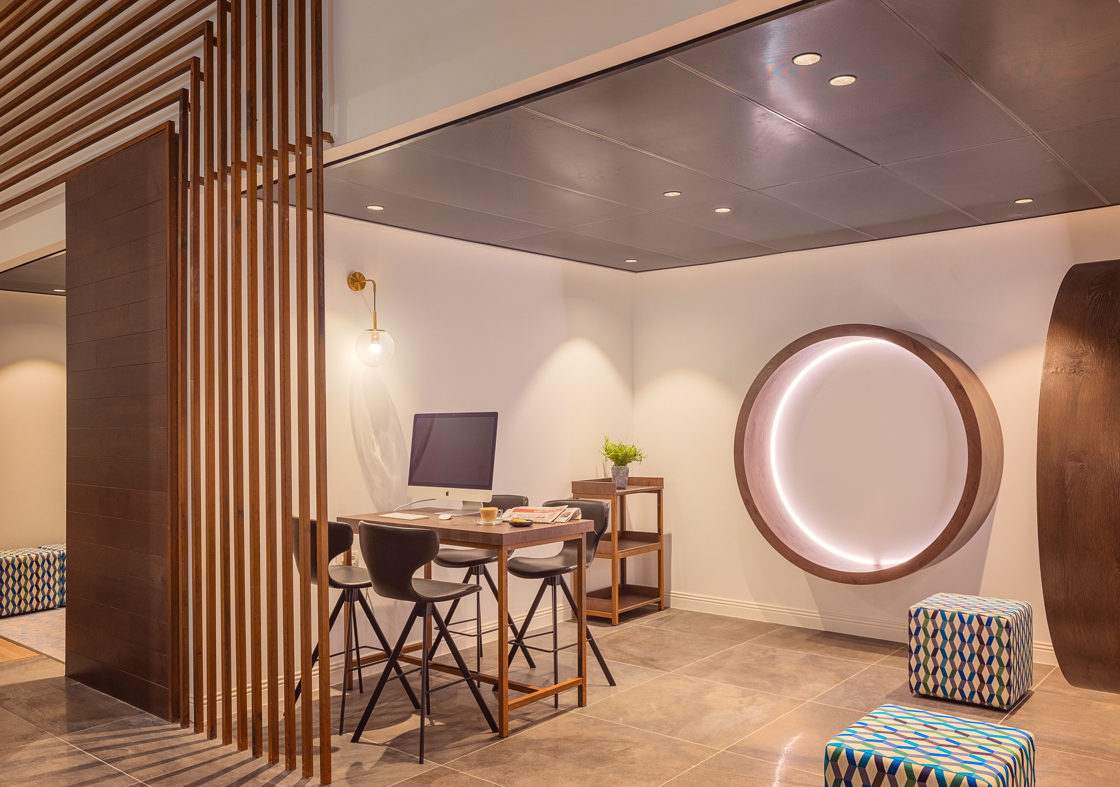 A modern dining area with a wooden table, chairs, and a unique circular light fixture on the wall.