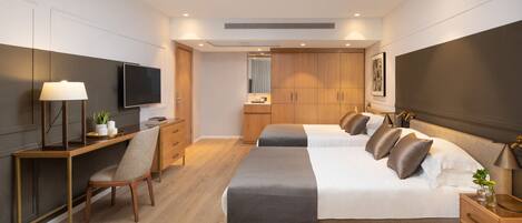 A modern hotel room with a large bed, a desk, a chair, a TV, and a wardrobe.