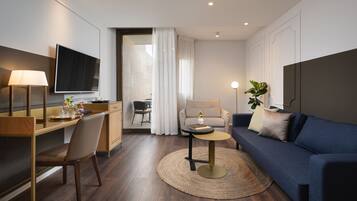 Ein modernes Hotelzimmer mit Schreibtisch, Stuhl, Sofa und Fernseher.