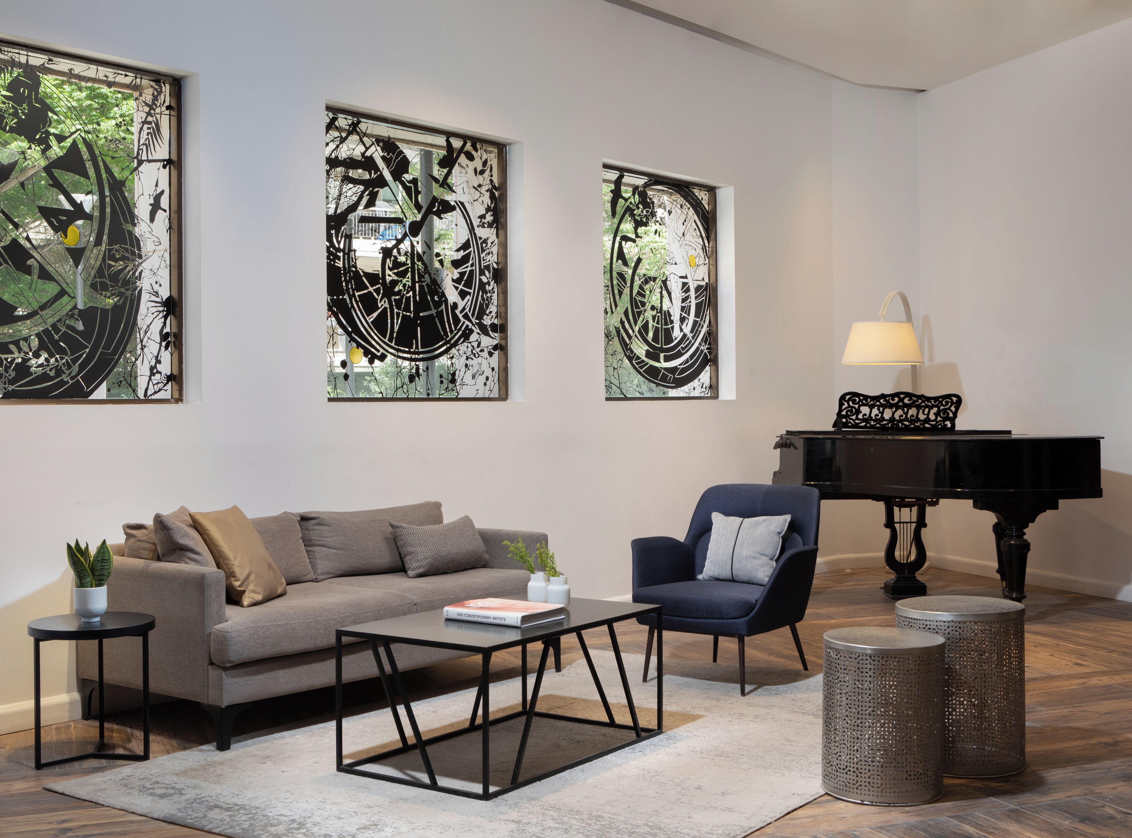 A modern living room with a sofa, armchair, coffee table, and a grand piano.