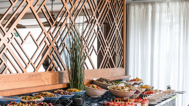 A buffet with various food items and a decorative wooden partition. - Cassia Hotel Jerusalem (Jerusalem)