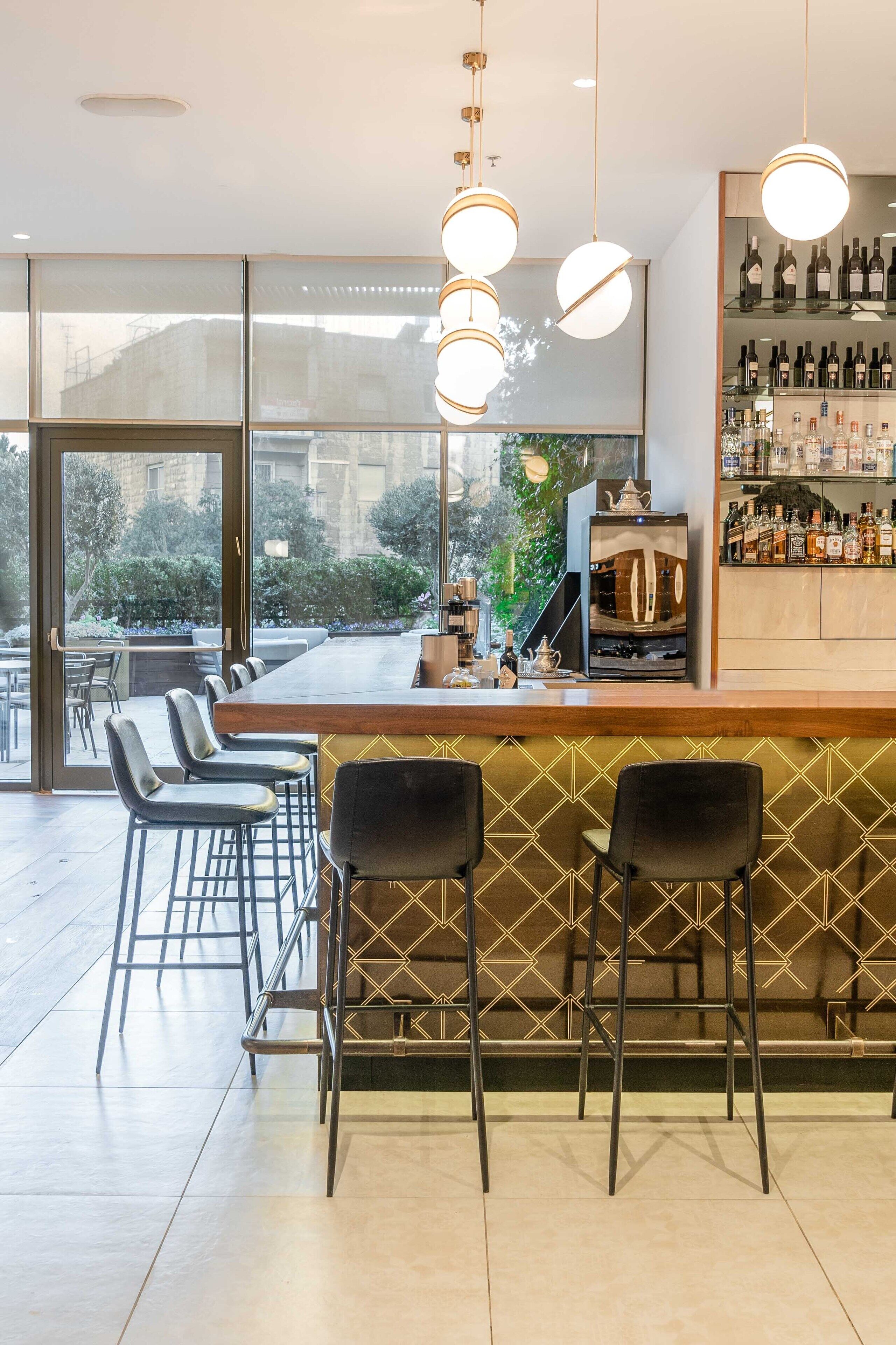 A bar area with a long counter, multiple bar stools, and a wine display.