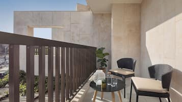 Ein Balkon mit Tisch, zwei Stühlen, einer Topfpflanze und Blick auf die Stadt.