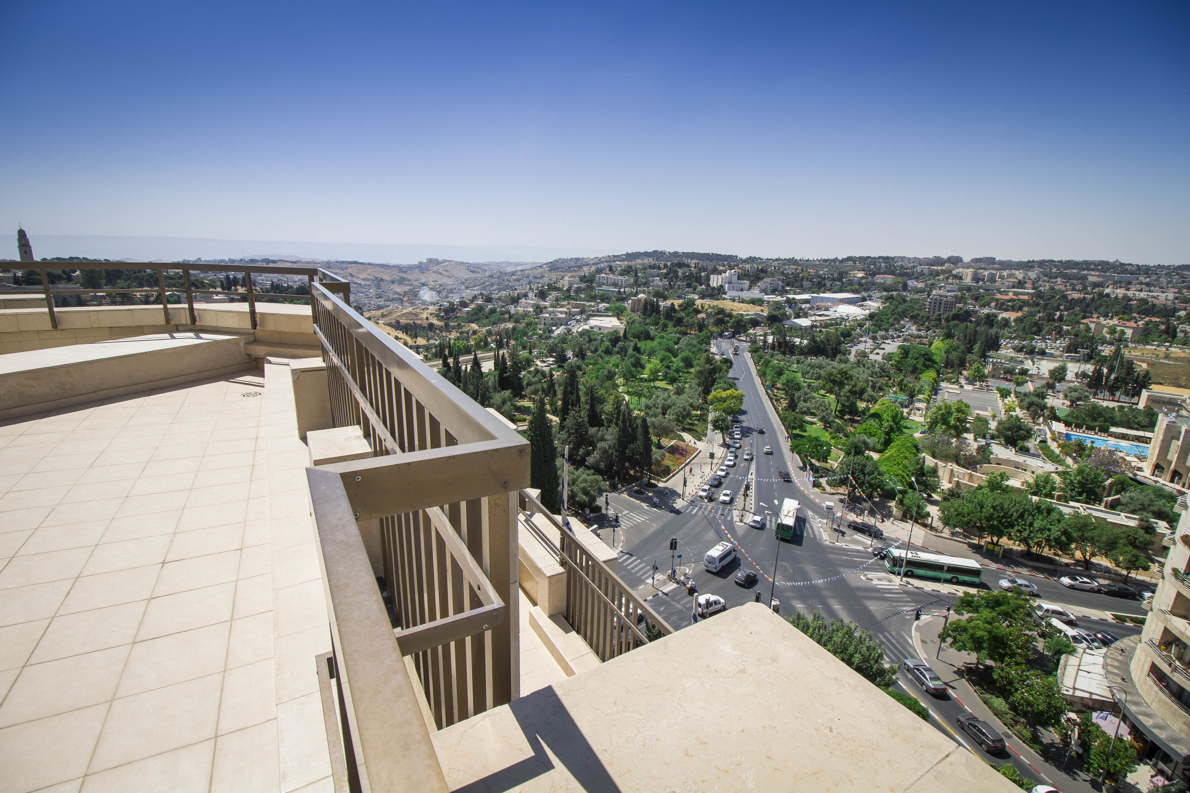 A high vantage point overlooking a cityscape with a clear sky, a road with vehicles, and buildings in the distance.