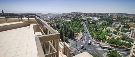 A high vantage point overlooking a cityscape with a clear sky, a road with vehicles, and buildings in the distance.
