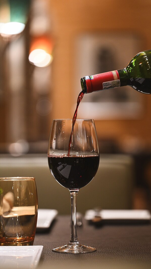 A wine glass being filled with red wine. - Fairmont The Norfolk (Nairobi)