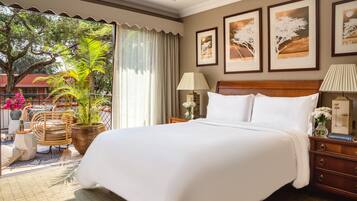 Habitación de hotel con una cama grande, dos mesitas de noche, un aparador, una ventana con cortinas y cuadros en la pared.