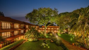A hotel with multiple floors, a well-maintained garden, and a large tree in the center. - Fairmont The Norfolk (Nairobi)