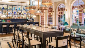 A spacious bar area with a long counter, multiple hanging light fixtures, and a variety of glassware on display. - Fairmont The Norfolk (Nairobi)