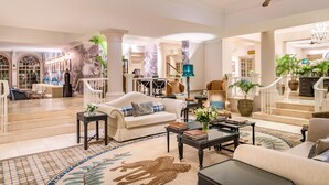 A spacious living area with a sofa, coffee table, and decorative plants. - Fairmont The Norfolk (Nairobi)