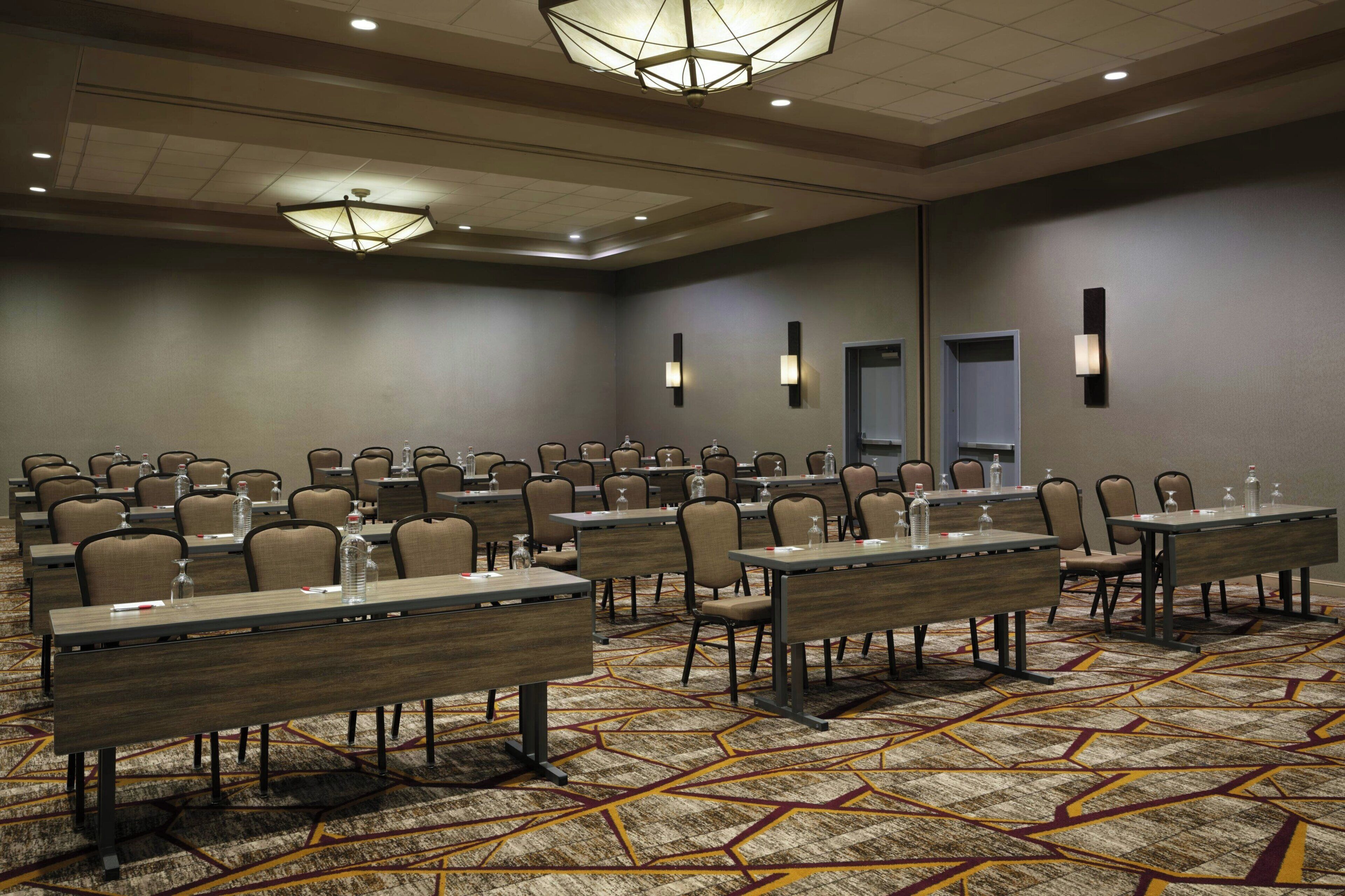 A conference room with multiple tables and chairs, equipped with water bottles and nameplates.