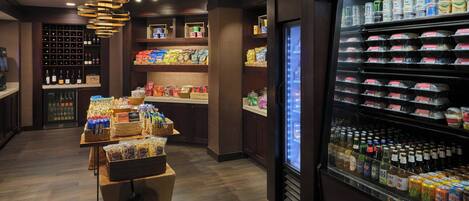 A well-lit store with shelves stocked with snacks, beverages, and bottled water.