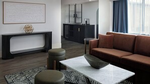 A modern living room with a sofa, ottoman, coffee table, and a fireplace.