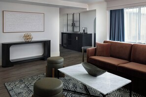A modern living room with a sofa, ottoman, coffee table, and a fireplace. - Marriott Raleigh Durham Research Triangle Park (Durham)